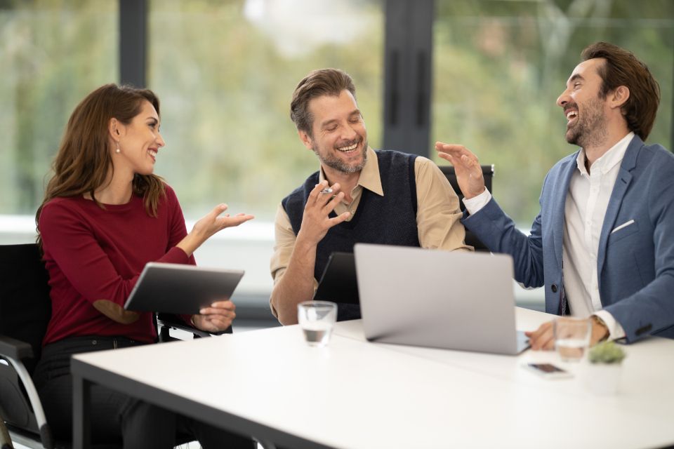 Three colleagues in discussion around a laptop